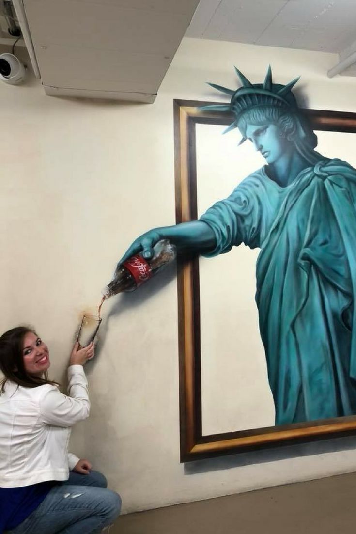 a woman is painting a statue of liberty on the wall