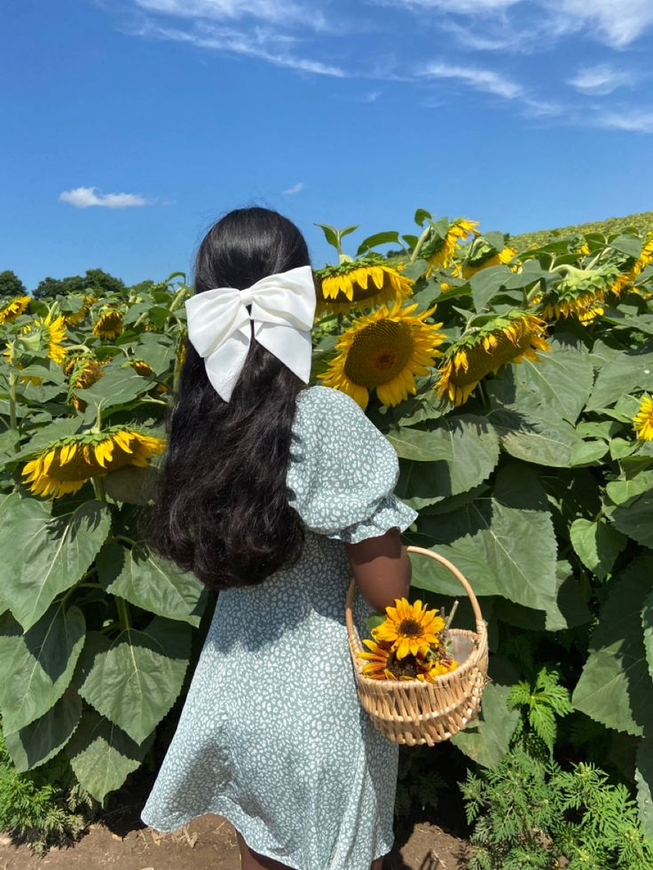 a girl in a sunflower field holding a basket