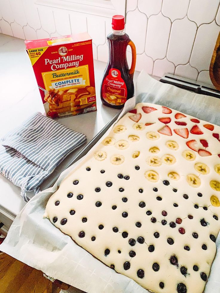 an uncooked pancake with fruit toppings on the counter next to baking utensils