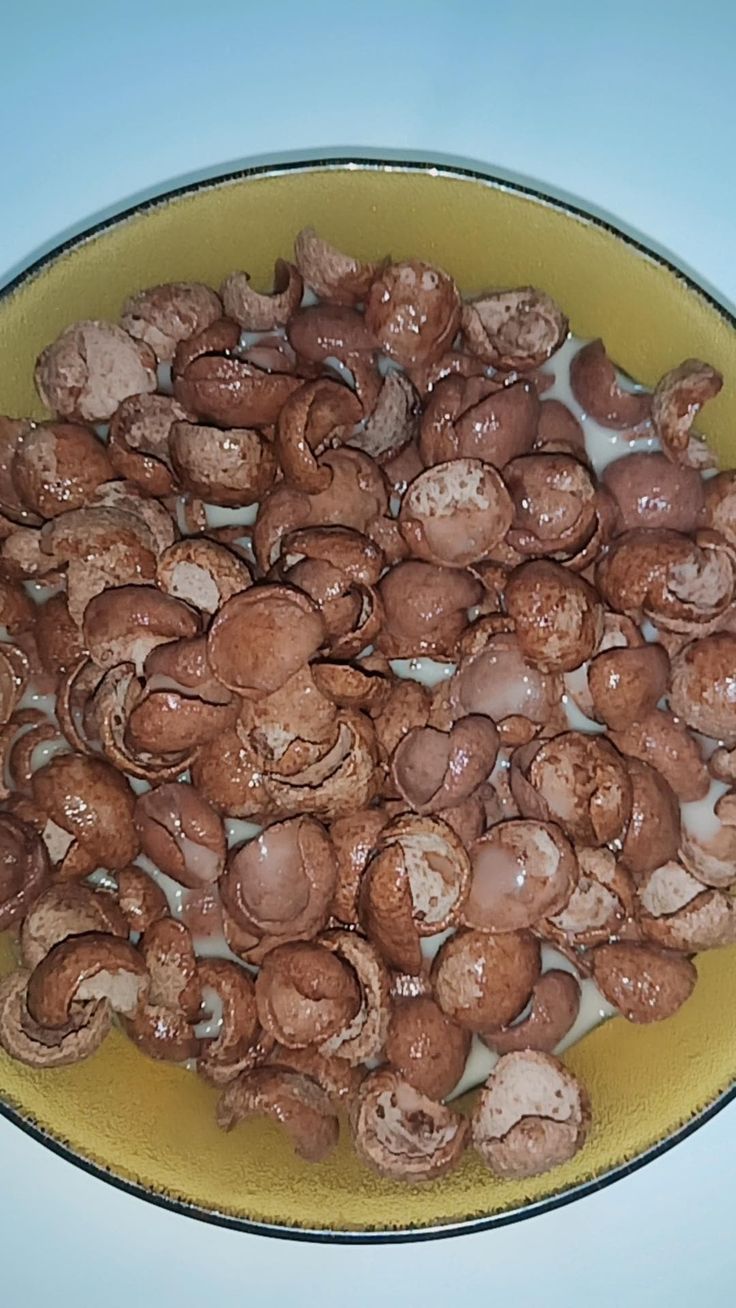 a yellow bowl filled with mushrooms on top of a table