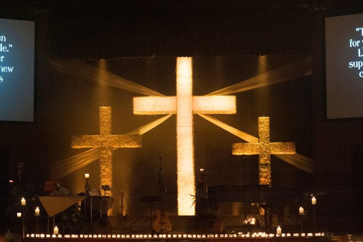 the cross is lit up in front of two large screens