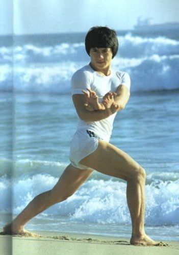 a man in white shirt and shorts doing yoga on the beach