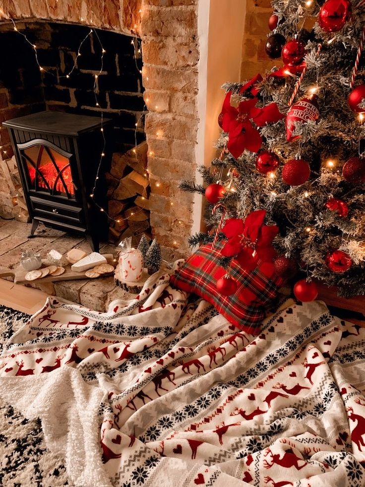 a christmas tree is next to a fireplace with red and black decorations on the mantle