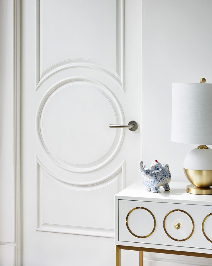 a white door with gold accents and a blue elephant figurine on a table