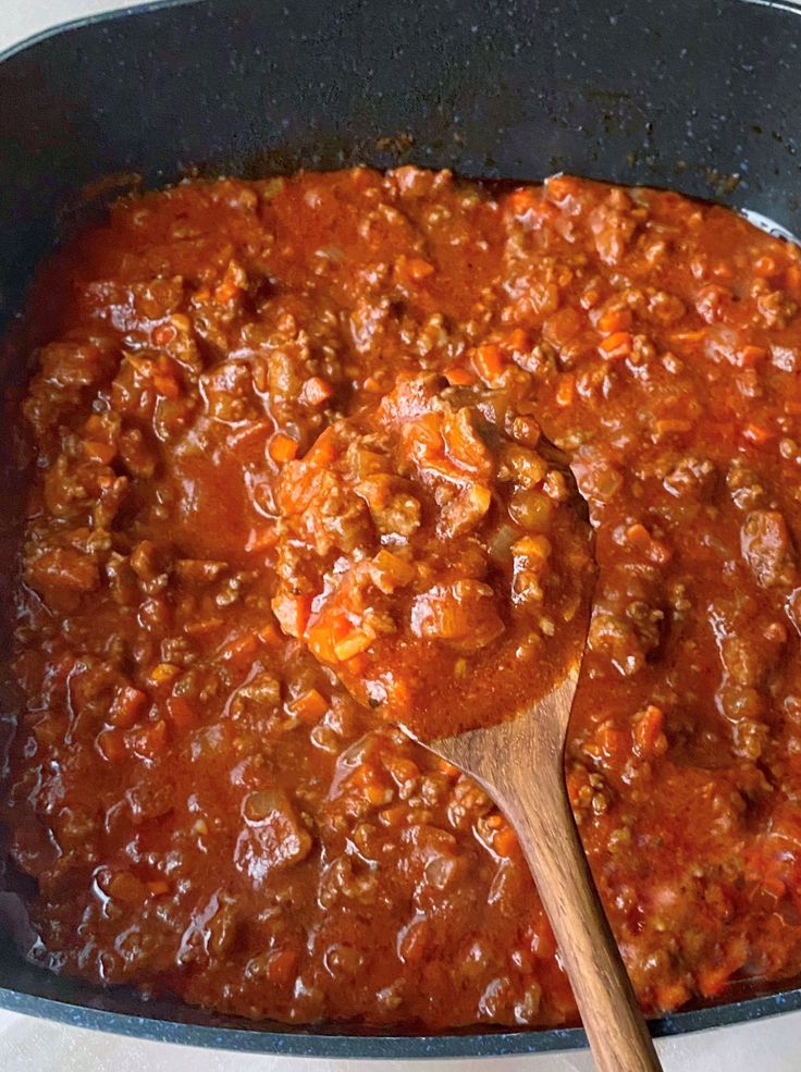 a skillet filled with chili sauce and a wooden spoon