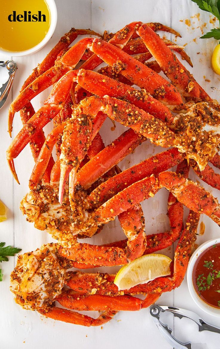 cooked crab legs with dipping sauce and lemon wedges