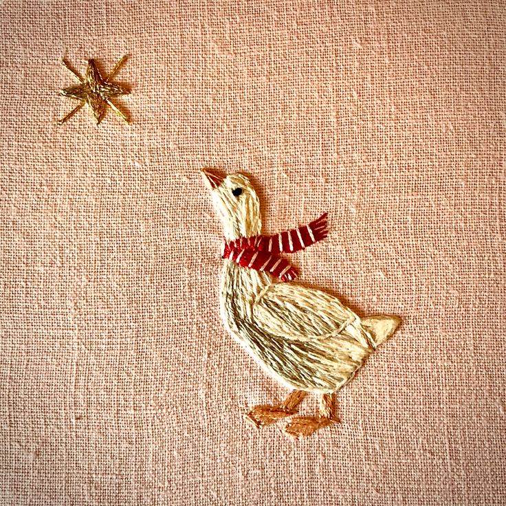 an embroidered bird with a red scarf on it's neck and star in the background