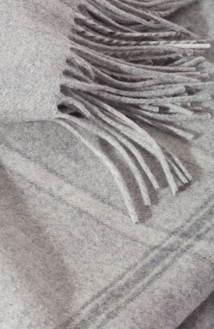 a gray blanket with fringes laying on top of it