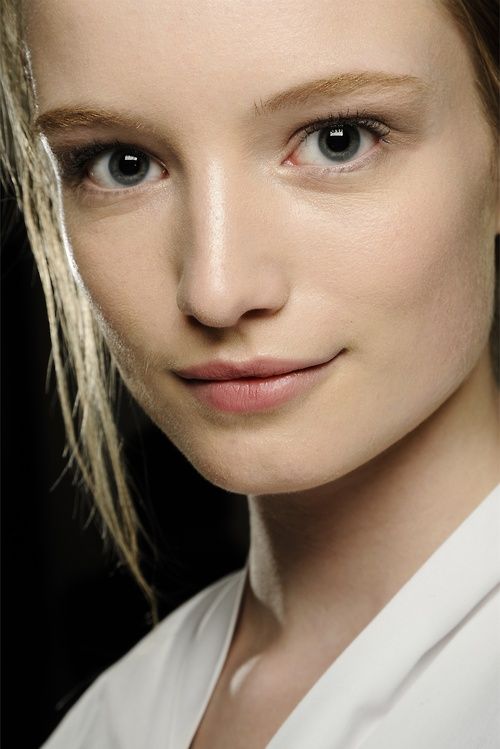 a woman with blonde hair and blue eyes is posing for a photo in front of a black background