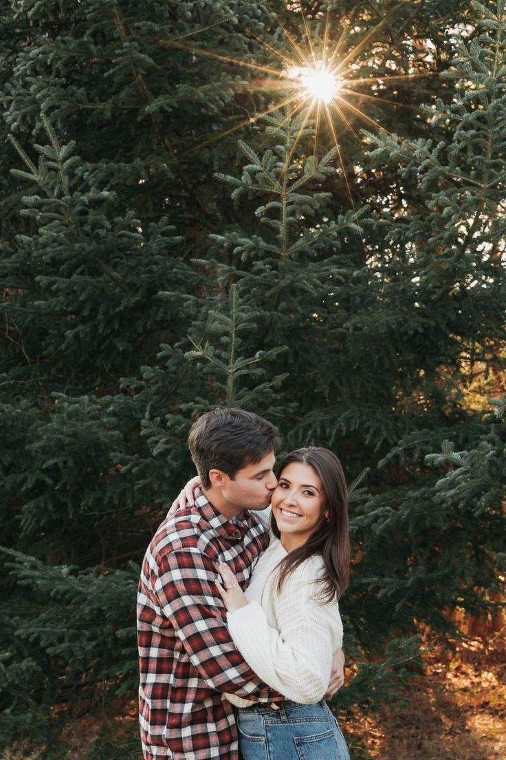 a man and woman embracing in front of trees