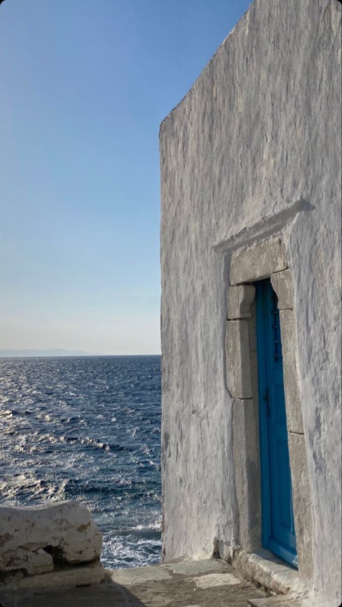 an old building with a blue door by the ocean