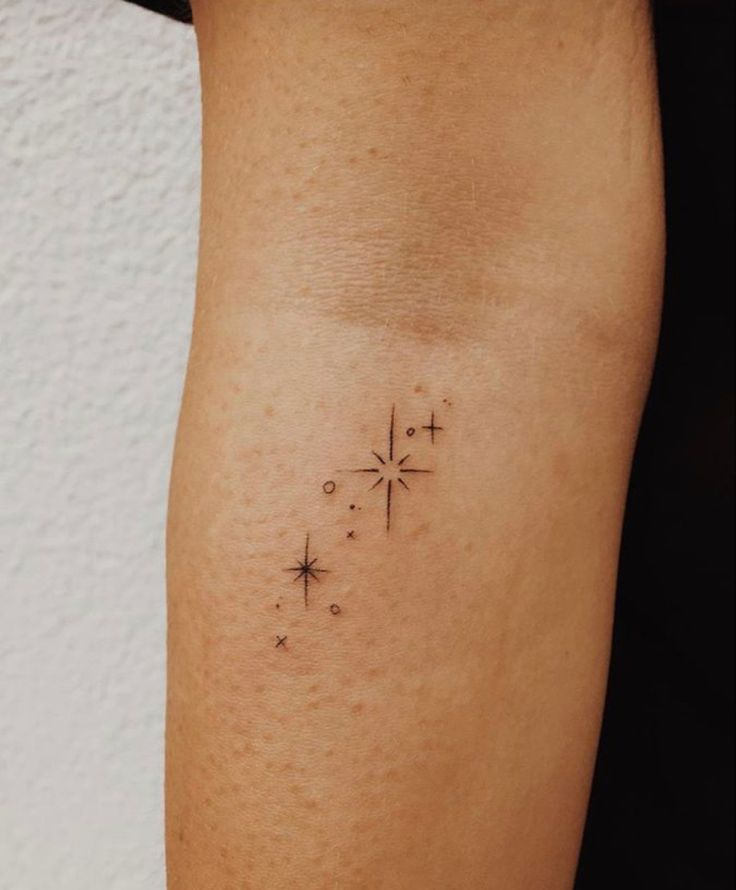 a small cross tattoo on the right arm and leg, with stars in it's center