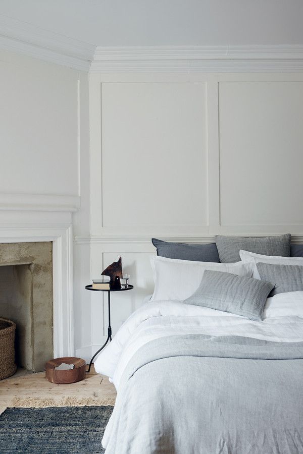 a bed with white sheets and gray pillows