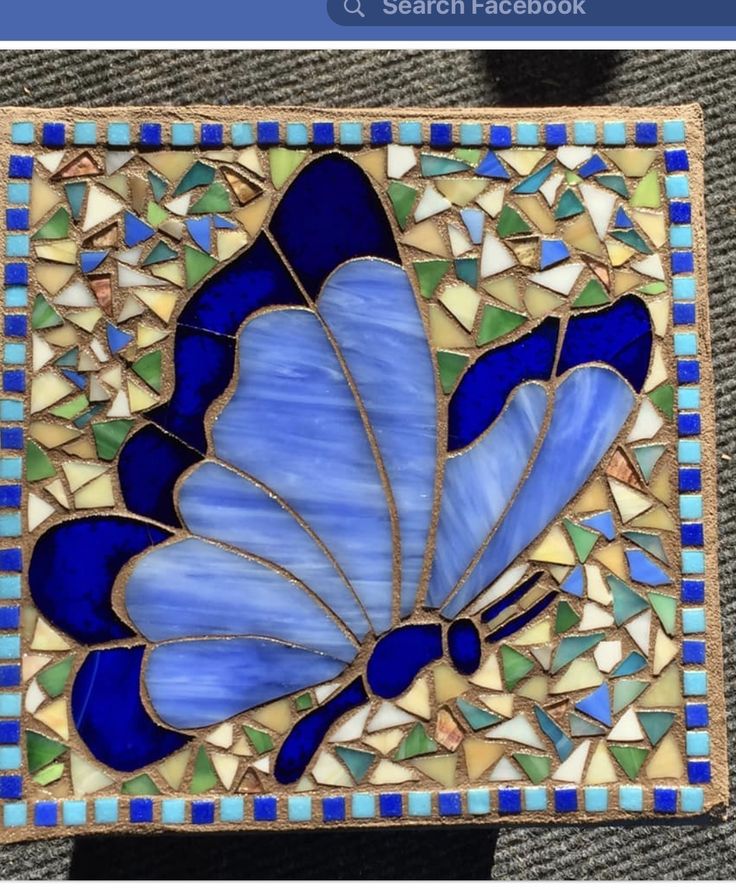 a blue butterfly is sitting on top of a piece of stained glass with small squares around it