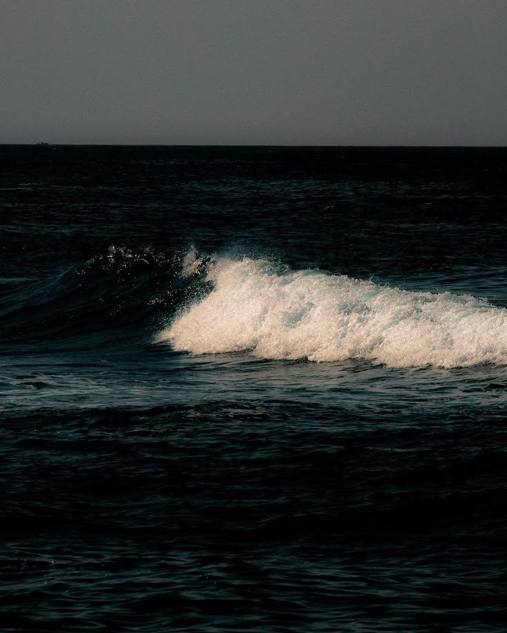 a person riding a surfboard on top of a wave in the ocean at night