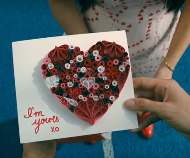 a woman holding up a card that says i'm yours xo with buttons in the shape of a heart