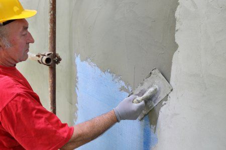 a man wearing a hard hat and red shirt painting a wall