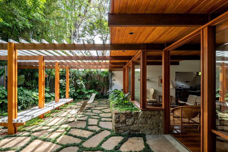 the inside of a house with stone walkways and wooden posts, surrounded by greenery