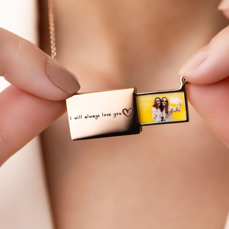 a woman is holding a necklace with a photo on it that says i will always love you