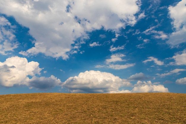 the sky is filled with fluffy clouds and brown grass