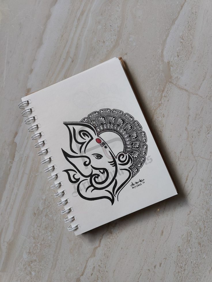 a spiral notebook with an elephant design on the front and back cover, sitting on a marble surface