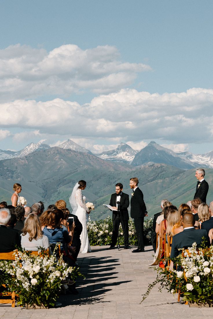 a couple getting married at the end of their wedding ceremony with mountains in the background