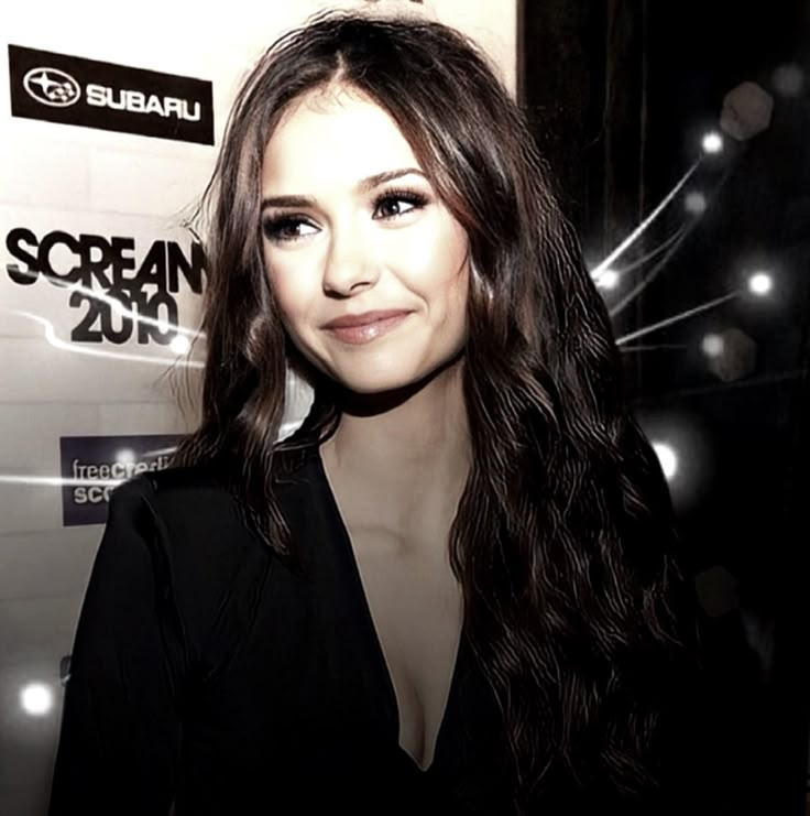 a woman with long hair standing in front of a sign