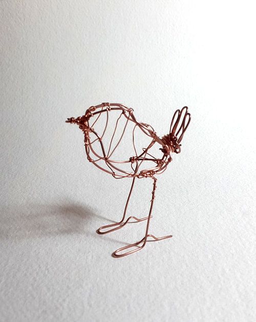 a wire bird sculpture sitting on top of a white surface