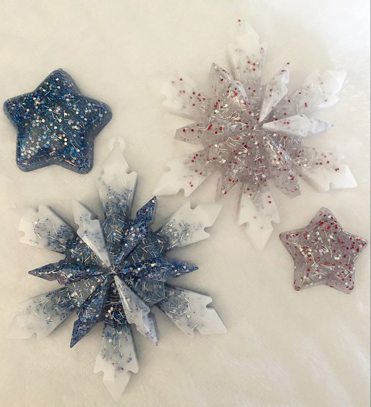 three snowflakes are laying on a white surface with red, white and blue glitter