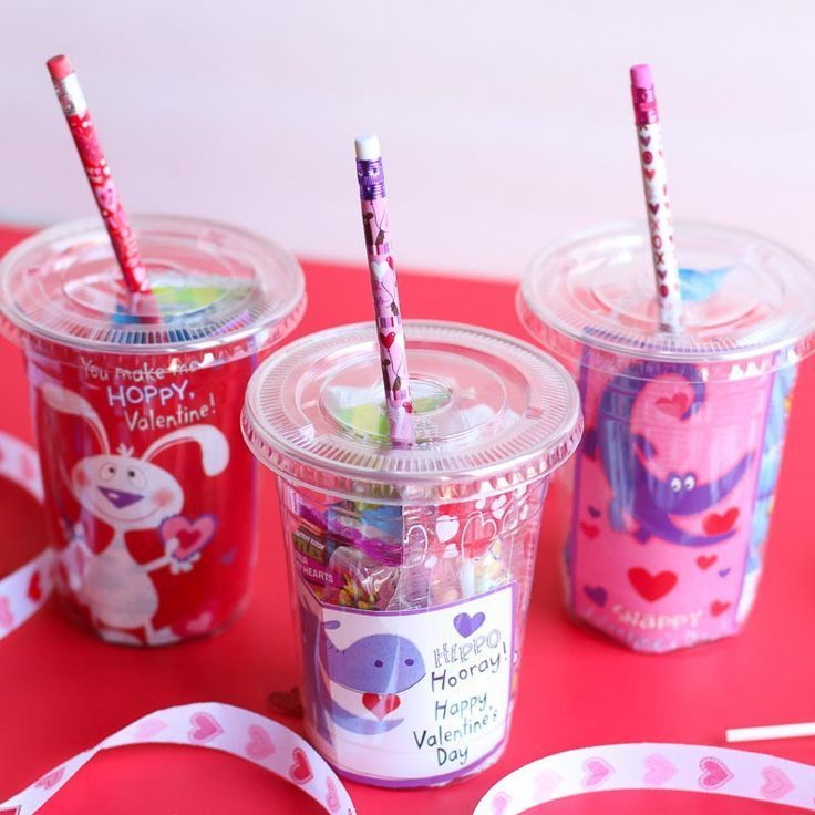 three plastic cups filled with candy and straws on top of a red tablecloth