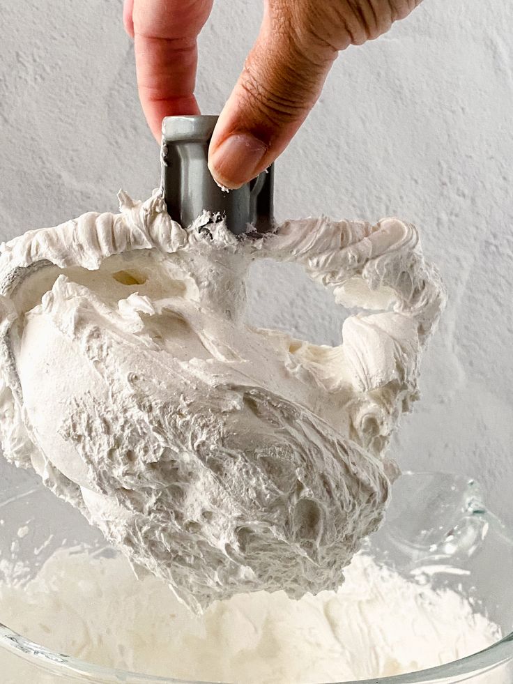 a person is mixing white frosting in a bowl