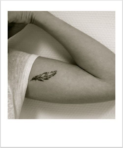 a woman with a feather tattoo on her arm