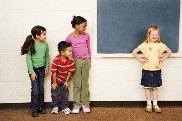 four children standing in front of a chalk board