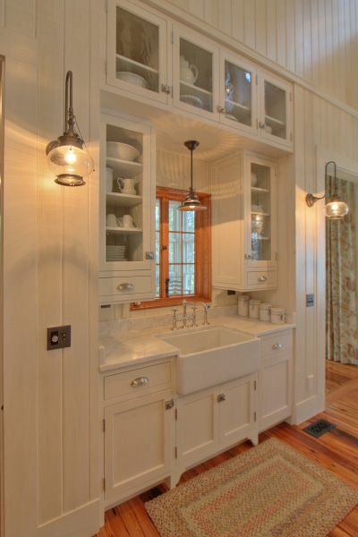 a large kitchen with white cabinets and wood flooring, along with a rug on the floor