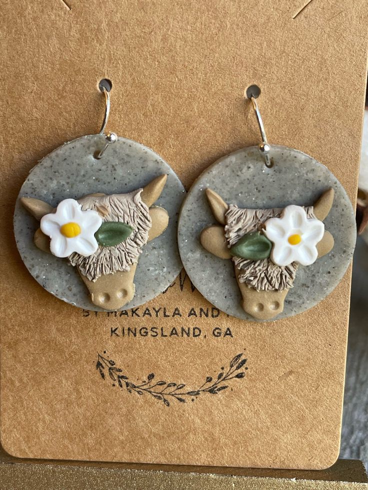 the earrings are decorated with white flowers and an animal's head on top of it