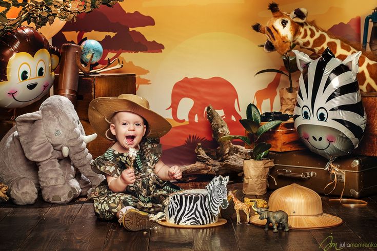 a baby is sitting on the floor surrounded by stuffed animals and giraffes