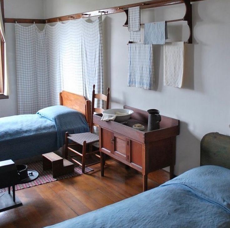 two beds in a room with wooden floors and blue sheets on the bed, next to each other