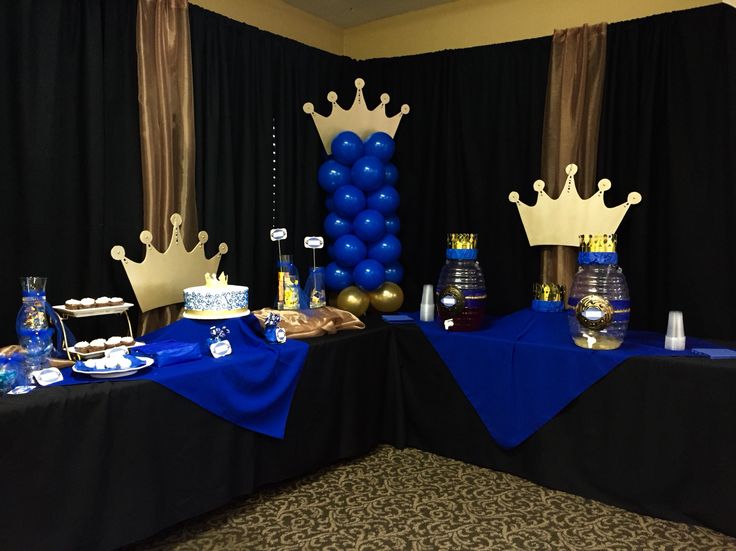 a table topped with blue and gold desserts next to black drapes covered walls