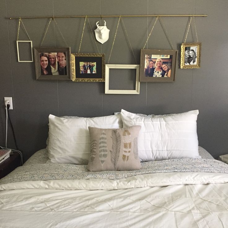 a bed with white sheets and pictures hanging on the wall above it's headboard