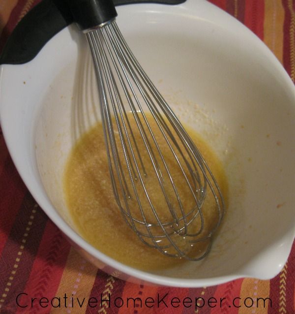 a whisk in a white bowl on top of a red and yellow table cloth