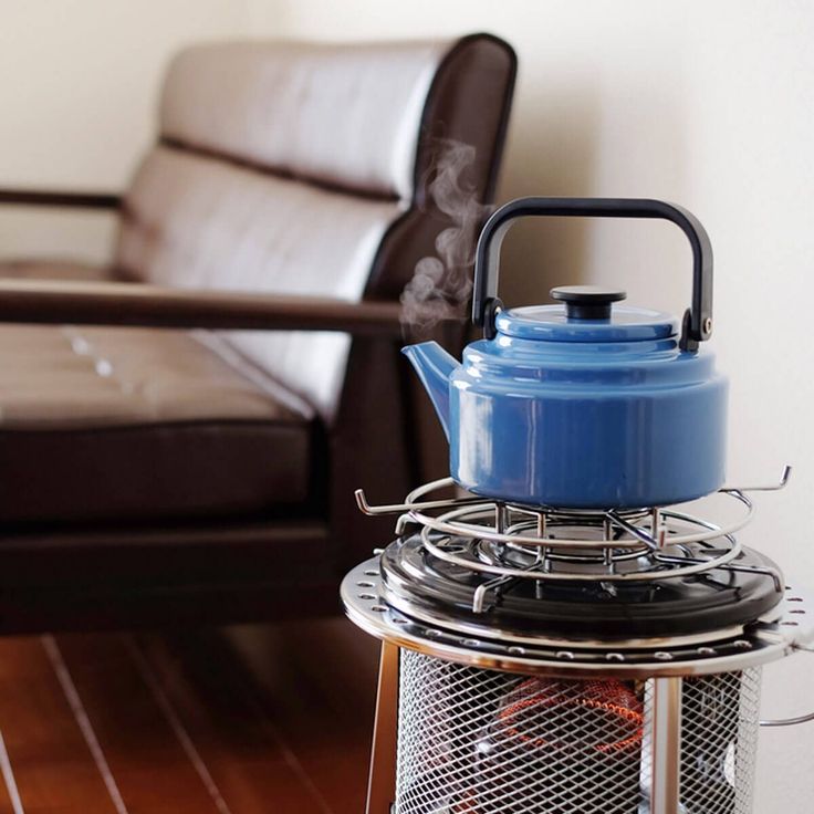 a blue tea pot sitting on top of a stove next to a brown leather chair