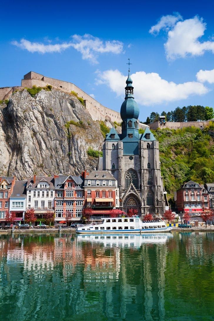 a boat is in the water near some buildings and a castle on top of a hill