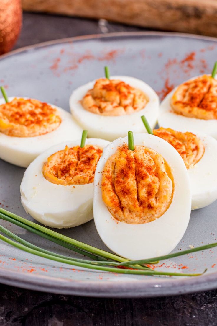 deviled eggs on a plate with chives and seasoning