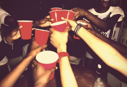 a group of people holding red cups in each other's hands with their fingers together