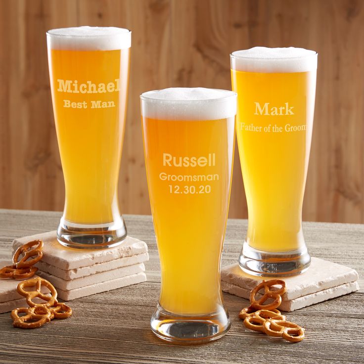 three beer glasses with personalized names and pretzels on the bottom, sitting on coasters