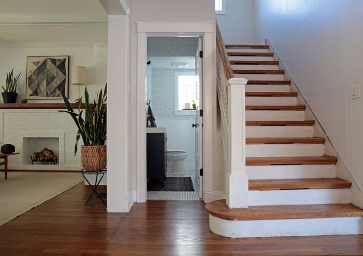 a staircase leading to a living room with a fireplace and potted plant in the corner