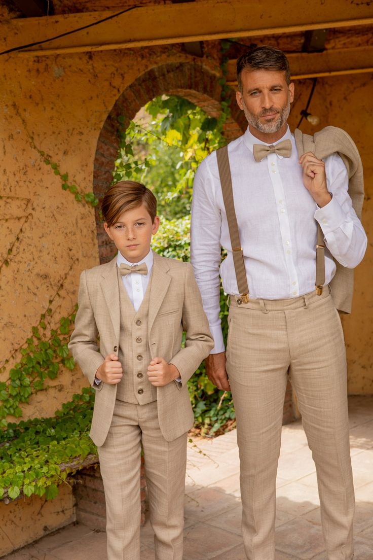 two young boys dressed in tan suits and bow ties, standing next to each other