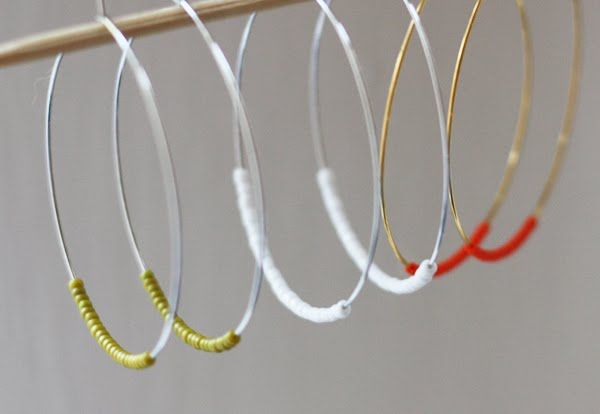 four pairs of hoop earrings hanging from a clothes line, with one red and one yellow