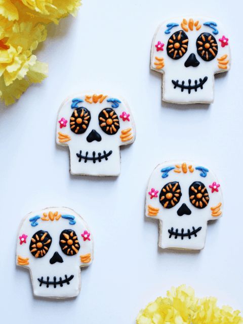 three decorated sugar cookies sitting on top of a white table next to a yellow flower