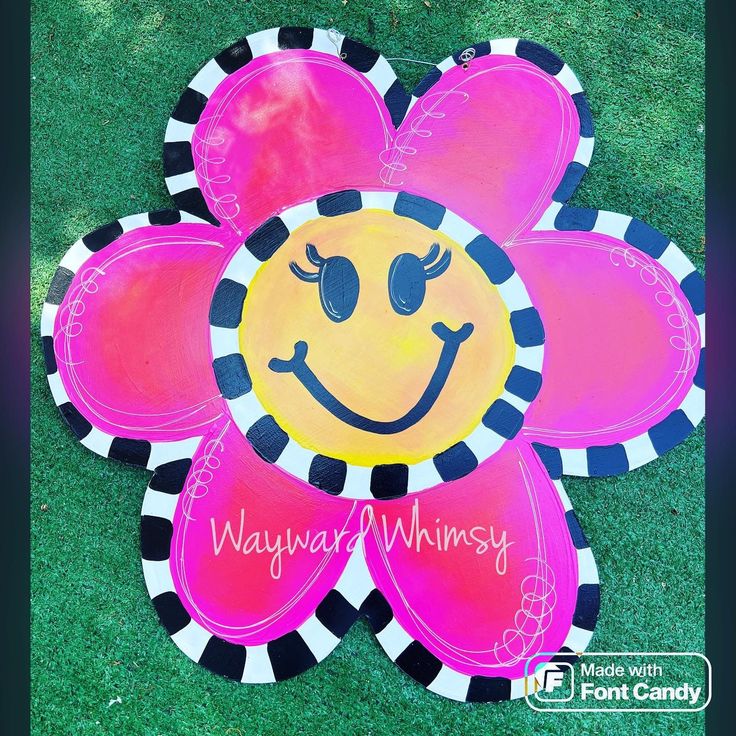 a pink and black flower with a smiley face painted on it's center piece